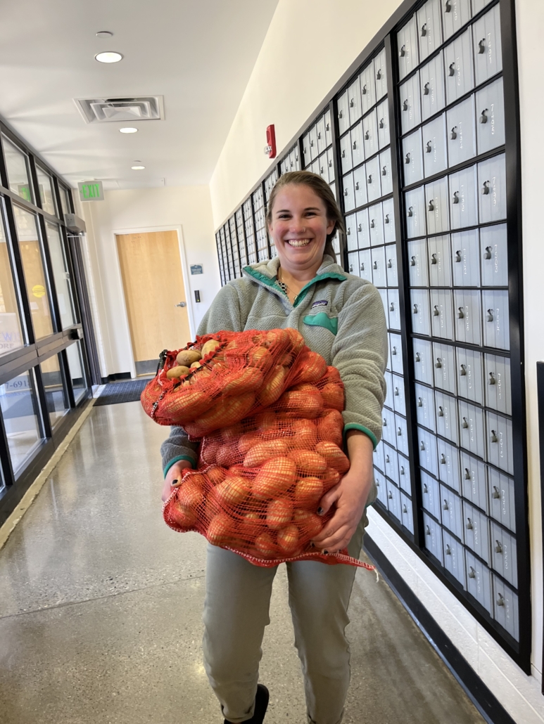 Caroline Hoge, VISTA Member with the Good Food Collective, carrying potatoes locally grown as part of the organization's Farms to Food Access Program